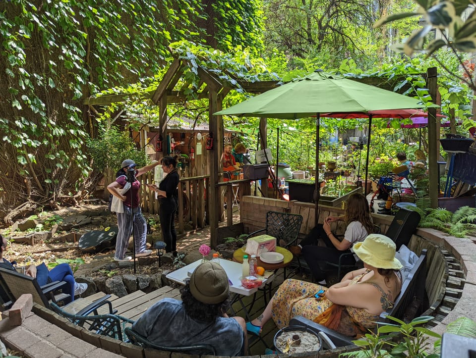 Many visitors in our community garden watching a free live music performance.